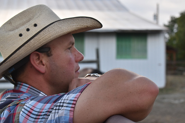 a cowboy leaning on a fence