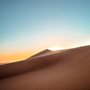 the sun rising over a sand dune