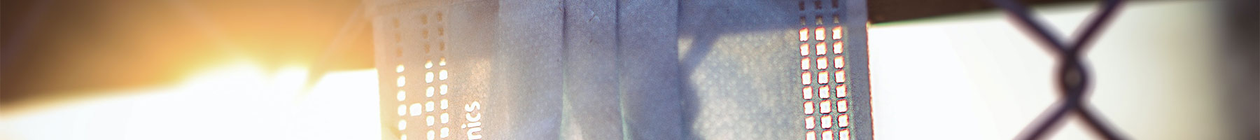 blue disposable mask hanging on a chain link fence