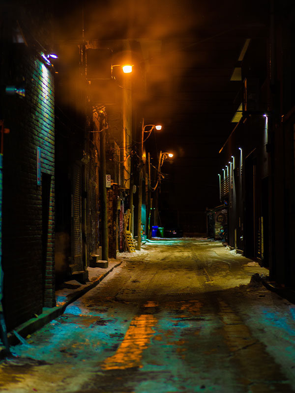 narrow, foggy alley lit by street lamps