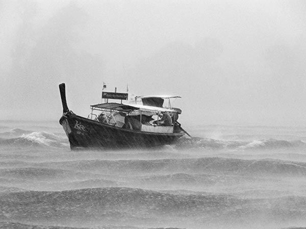 small boat in rough water with rain and clouds