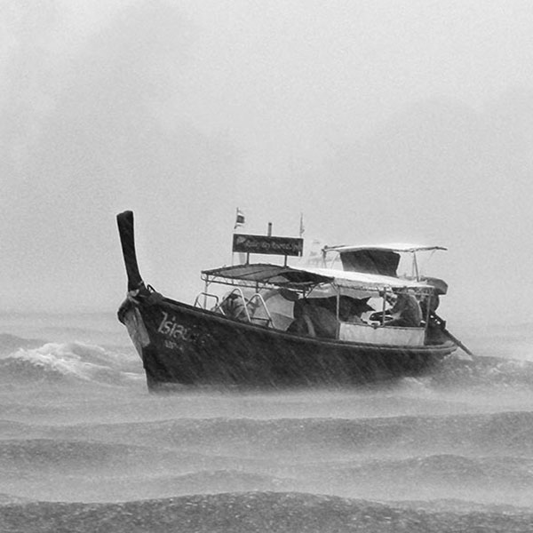 small boat in rough water with rain and clouds