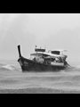 small boat in rough water with rain and clouds