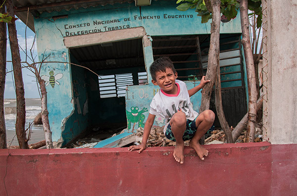 a little boy sitting on a red wall