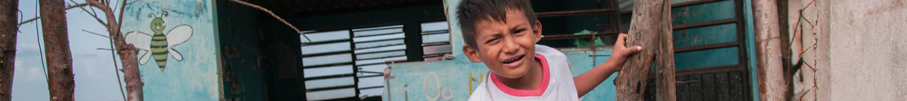 a little boy sitting near a damaged building