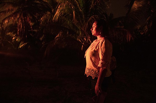 a woman standing in the darkness, illuminated by a red light