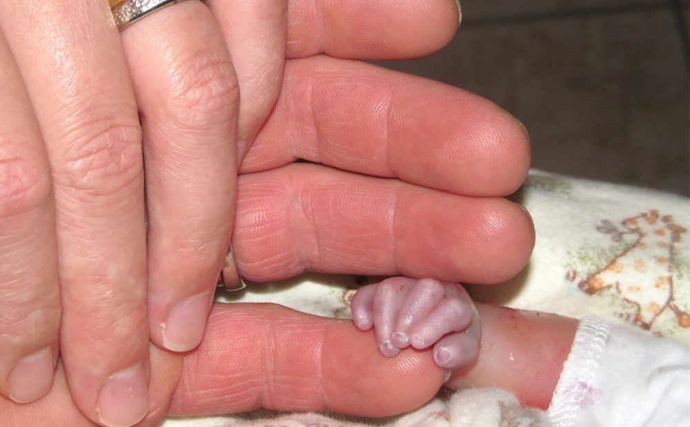 Linked hands of father, mother and stillborn baby