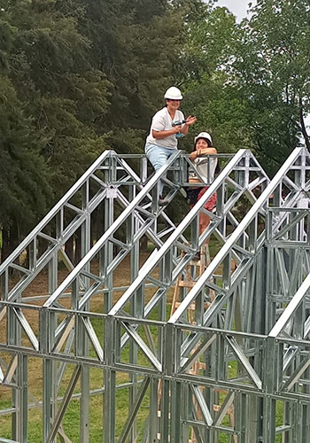 two workers building a roof on a house
