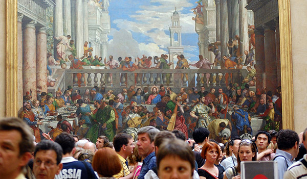 a crowd of people viewing a painting in a museum