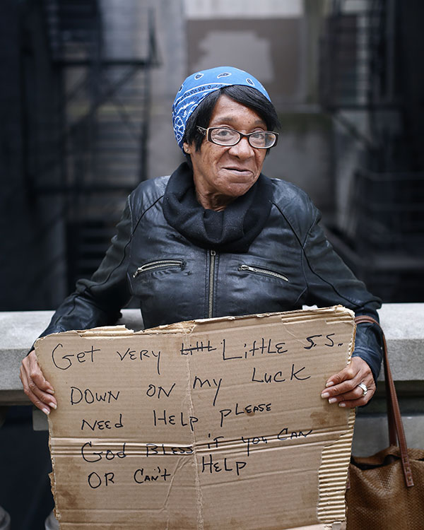 homeless woman carrying a cardboard sign