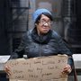 homeless woman carrying a cardboard sign
