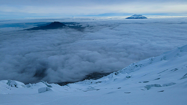 Snowcapped mountains peeping up from cloud layer