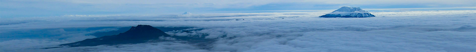 Snowcapped mountains peeping up from cloud layer