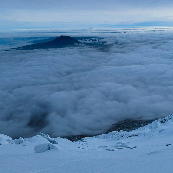 Snowcapped mountains peeping up from cloud layer