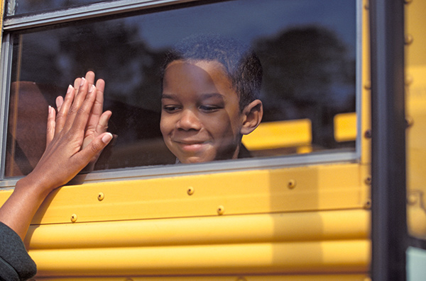 a boy looking out the window of a yellow school bus