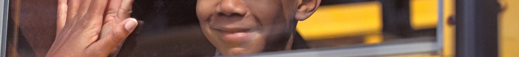 a boy looking out the window of a yellow school bus
