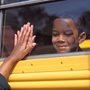 a boy looking out the window of a yellow school bus