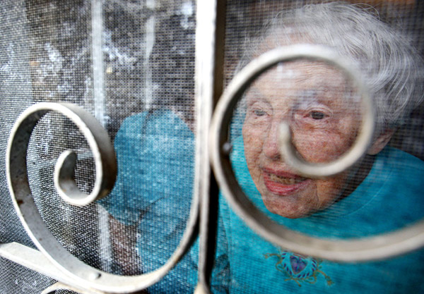 an old woman looking through a screen door at Christmas carolers