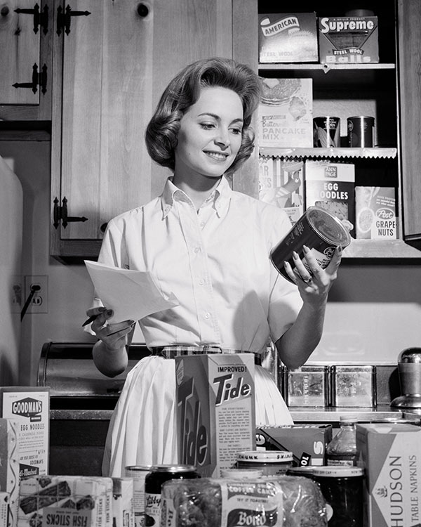 a woman with groceries in a kitchen