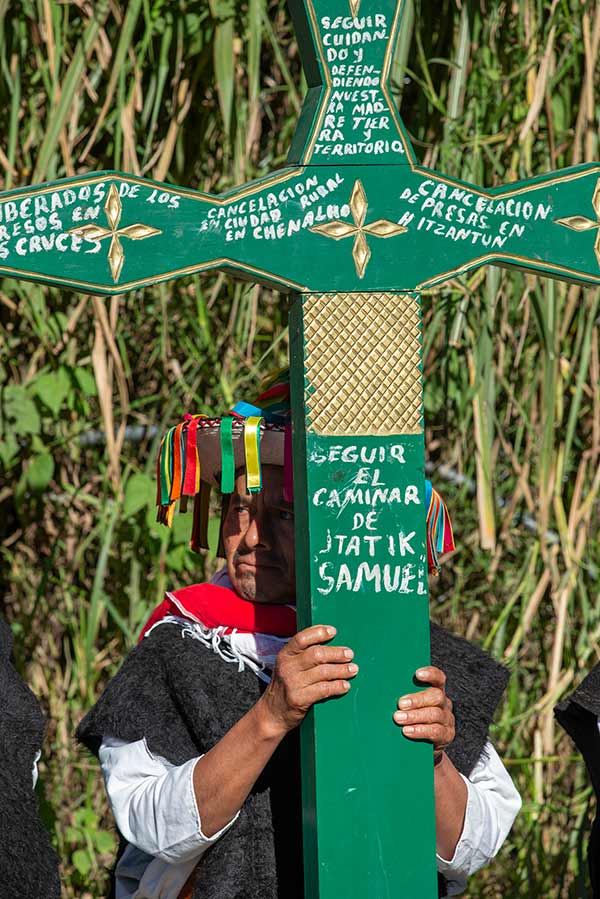 a man carrying a green cross