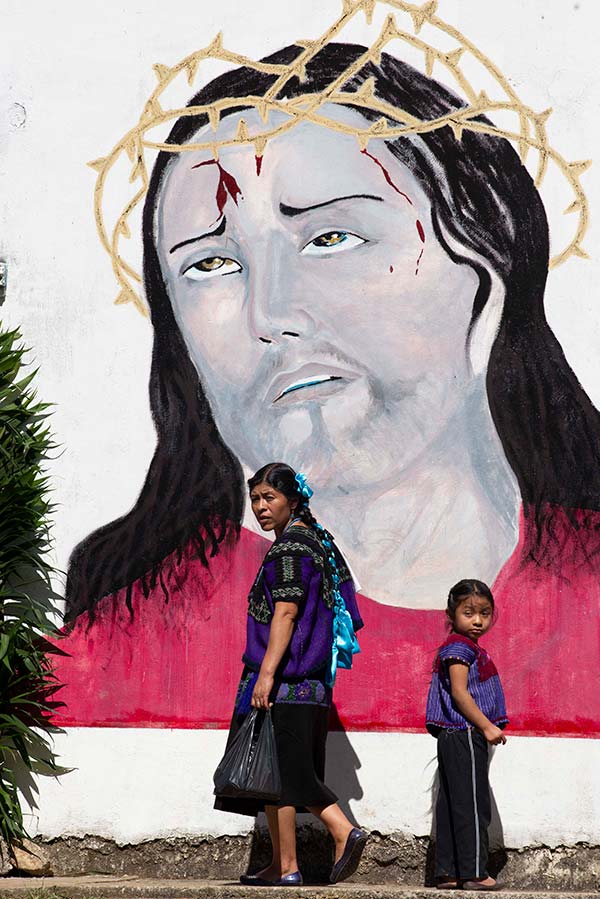 a child and woman in front of a mural of Jesus