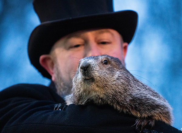 a man holding a groundhog on Groundhog Day