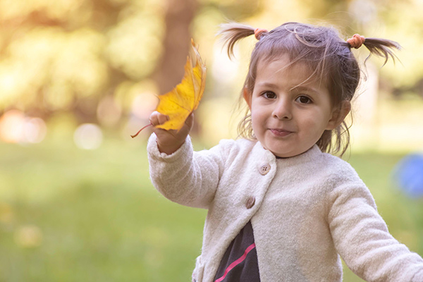 a child holding a yellow leaf