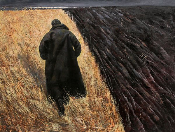 man walking past plowed field