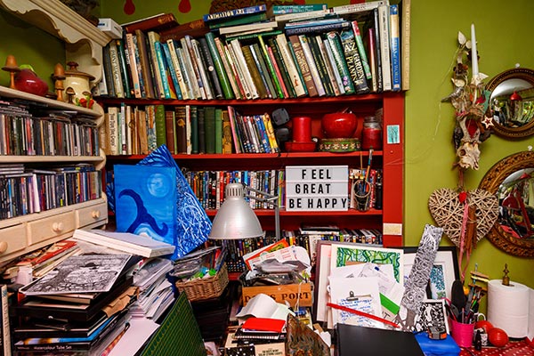 cluttered shelves filled with books, antiques and art