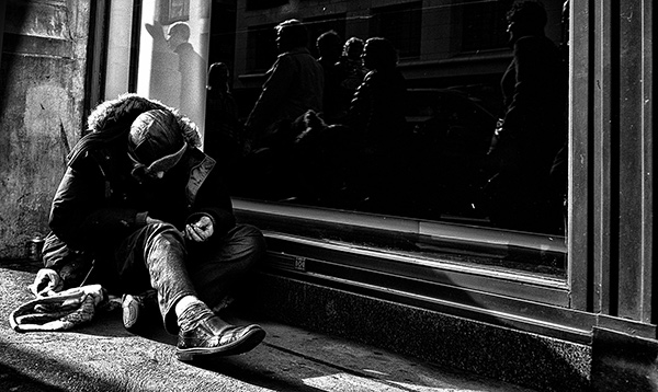 a homeless man sitting by a storefront window