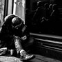 a homeless man sitting by a storefront window