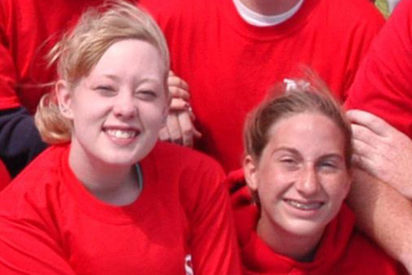 two teenage girls pose with a group