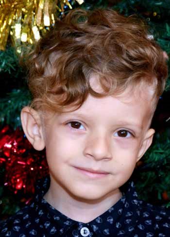 A boy with a Christmas tree behind him