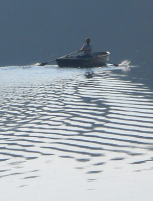 boy in a rowboat on a lake at dawn
