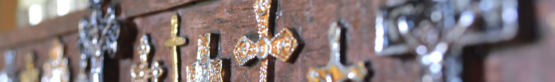 Many crosses of differing metals on a wooden background