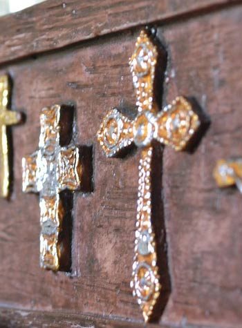 Many crosses of differing metals on a wooden background