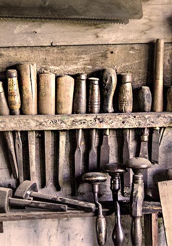 a collection of chisels and hammers at a work bench