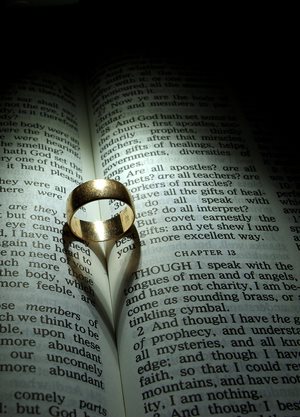 Wedding ring sitting on a Bible open to 1 Corinthians 13.