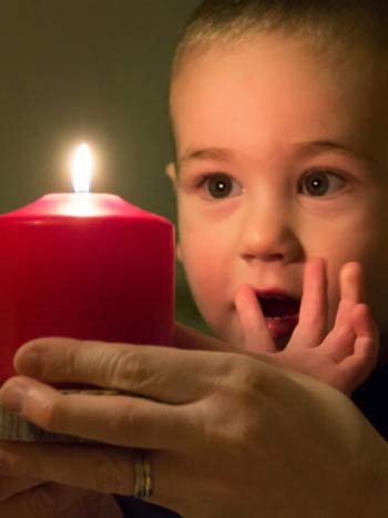Toddler looking at a candle with wide eyes.