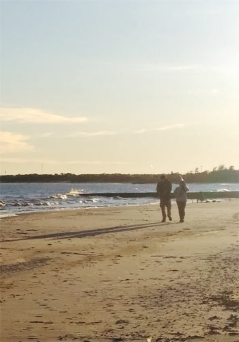 A couple walking on the beach in the evening