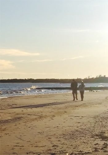 A couple walking on the beach in the evening