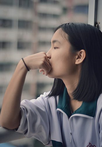 a young asian woman gazing out a window