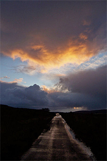 sun setting over a dark road