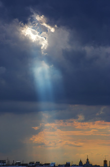 sun shining through clouds onto a city