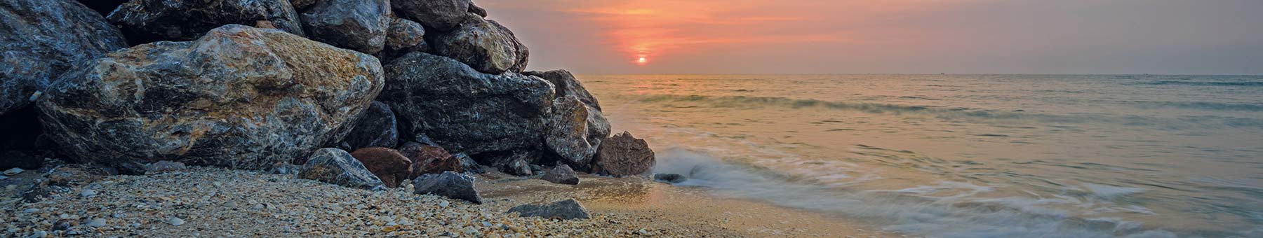 the sun setting over a rocky beach