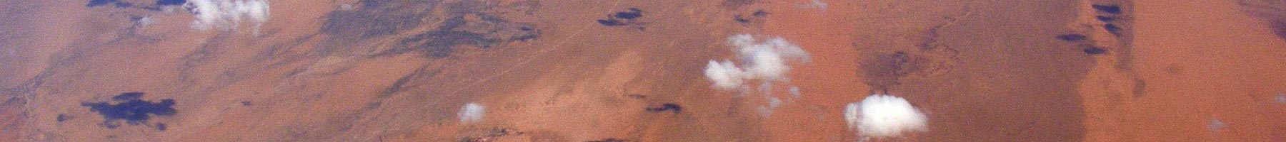 Photograph of a view flying above clouds looking down on the Sahara desert.