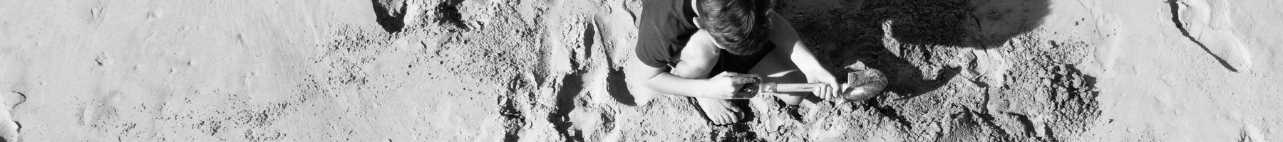 a boy playing in a sandpile