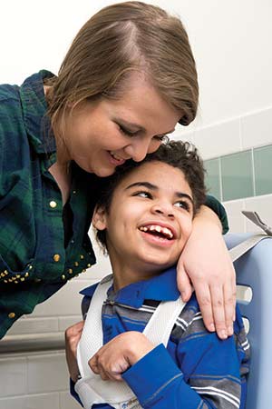 disabled boy lying in smiling caregivers lap
