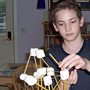 A home-schooled boy building a structure with marshmallows and sticks.