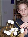 A home-schooled boy building a structure with marshmallows and sticks.